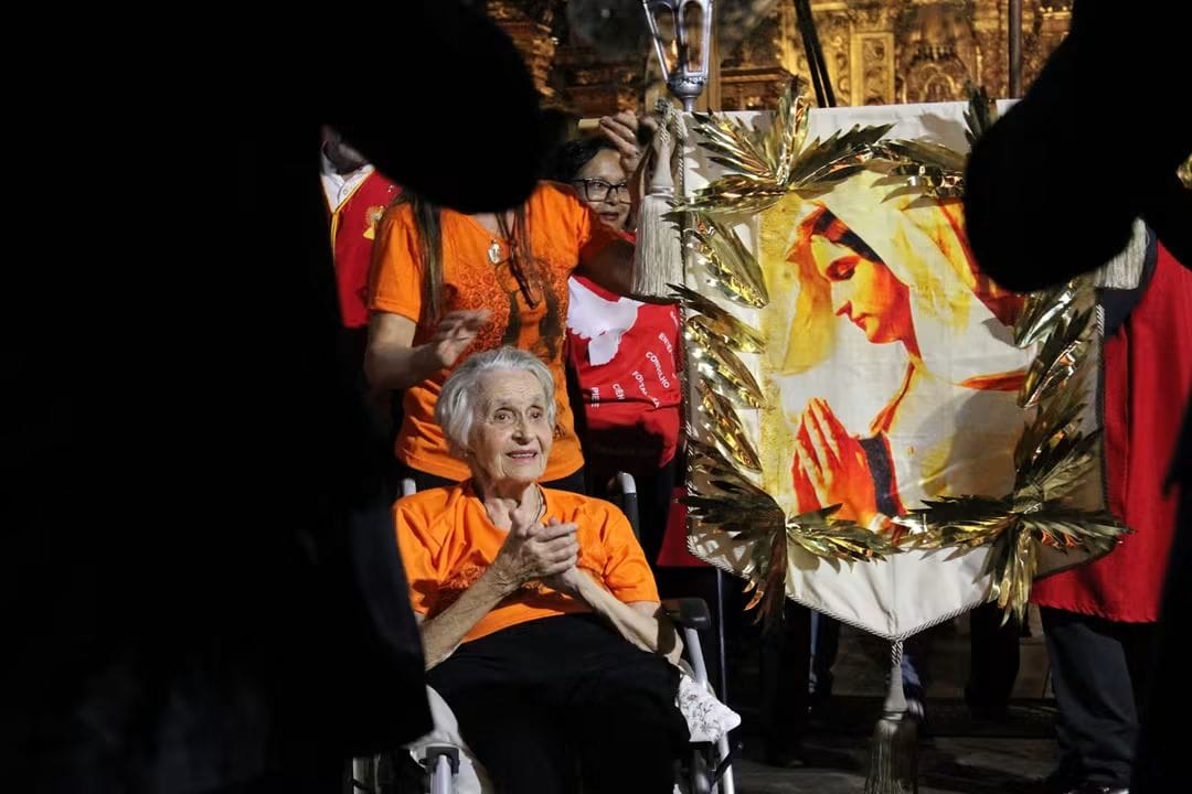 Devota acompanha a celebração ao lado de um estandarte de Nossa Senhora